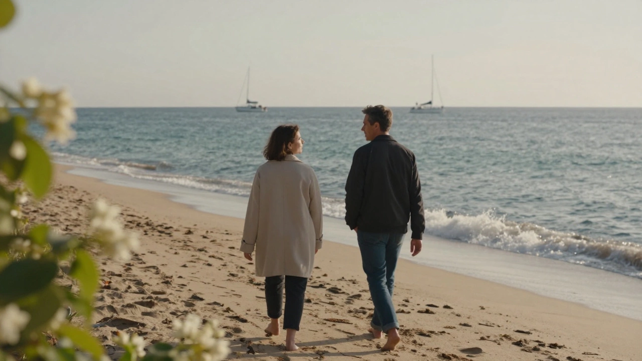 Two people walk barefoot along a dawn-lit beach in Saint-Tropez, lost in quiet conversation.